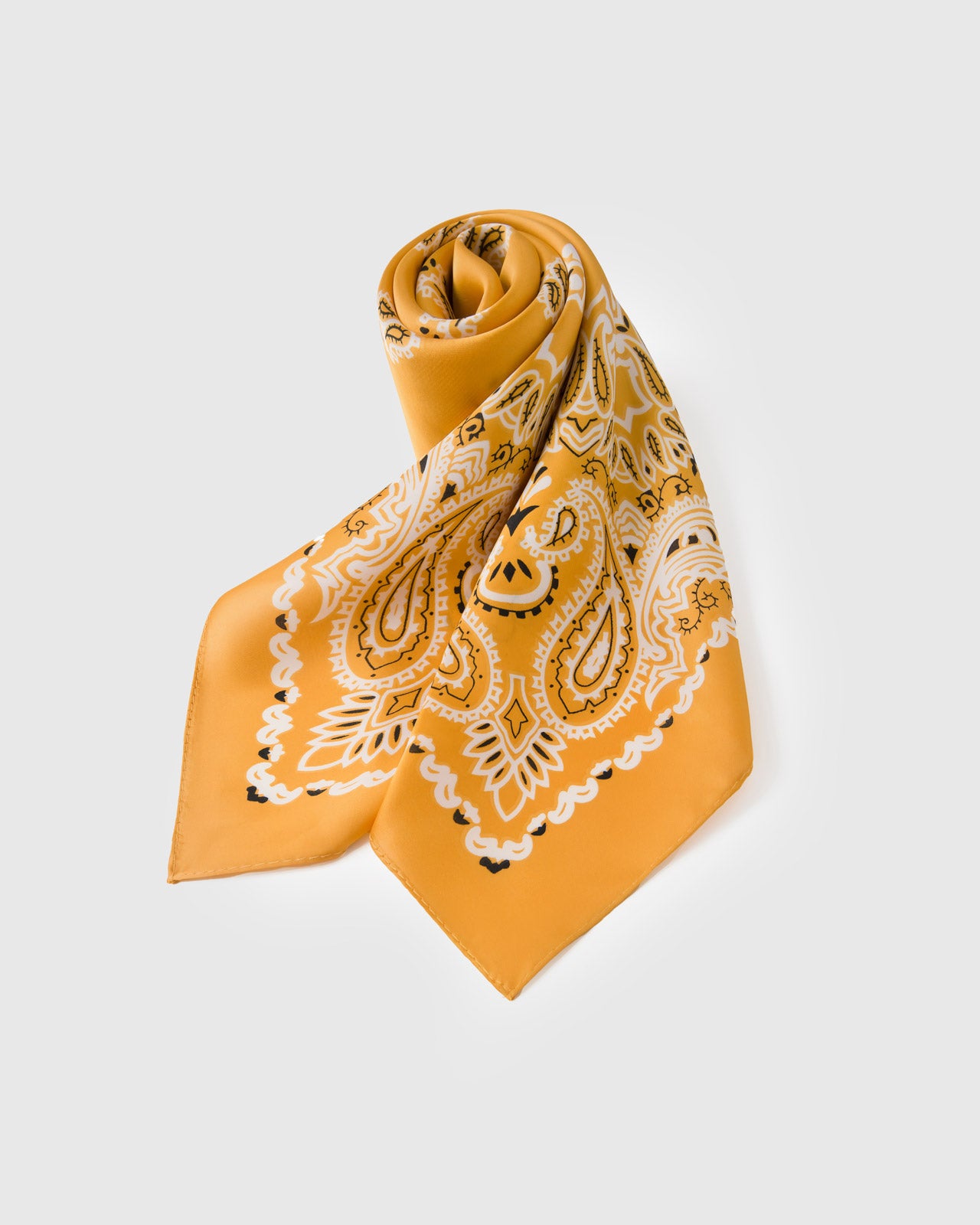 Rolled saffron silk scarf knotted to show the paisley motif and the small-square bandana format
```
