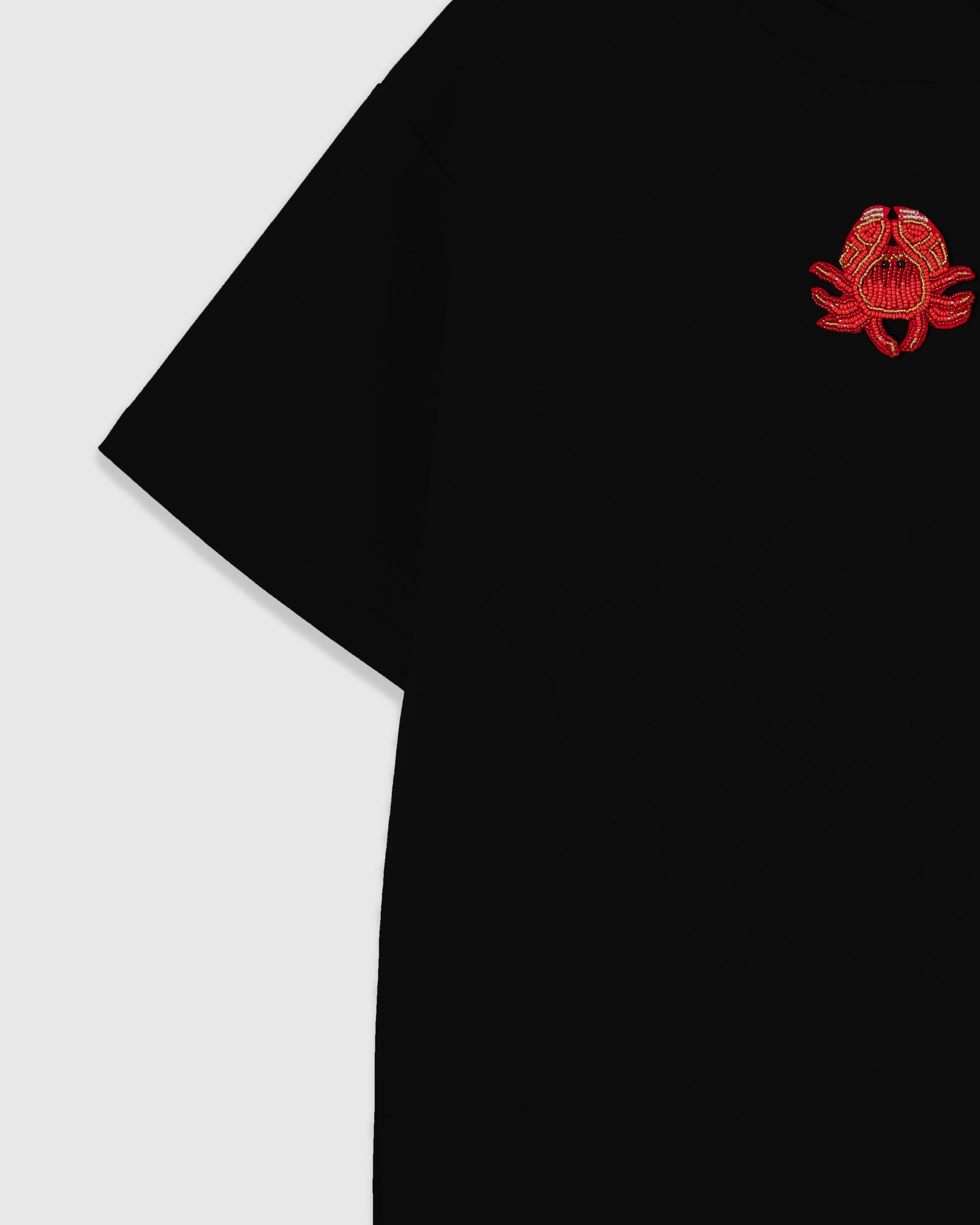 Detail of the raised crab applique near the shoulder showing beaded claws and crystal accents sewn onto black cotton.