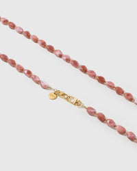 Macro close-up of the polished dusty-rose resin beads and gold-plated clasp, each strap assembled by hand