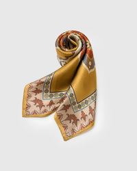 Saffron silk scarf folded into a triangular drape showing the medallion field and the taupe rosette border
```