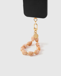 Blush marble phone strap hanging from black phone case showing wrist carry with warm stone beads