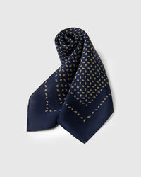 Rolled silk scarf showing the navy paisley field meeting the thin gold border line
```