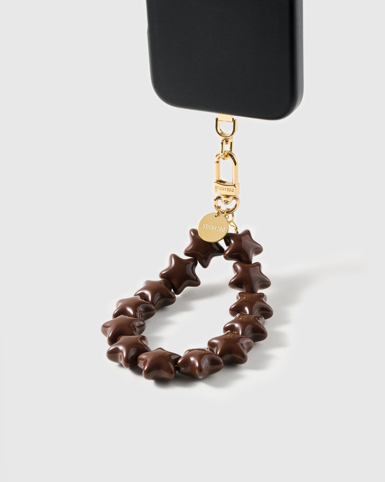 Loved by Thousands — cocoa star bead strap clipped to a black phone case showing the wristlet loop and gold hardware