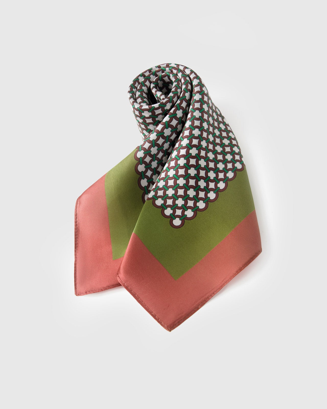 Rolled silk scarf knotted to show the tile mosaic print framed by the olive and rose-coral borders
```