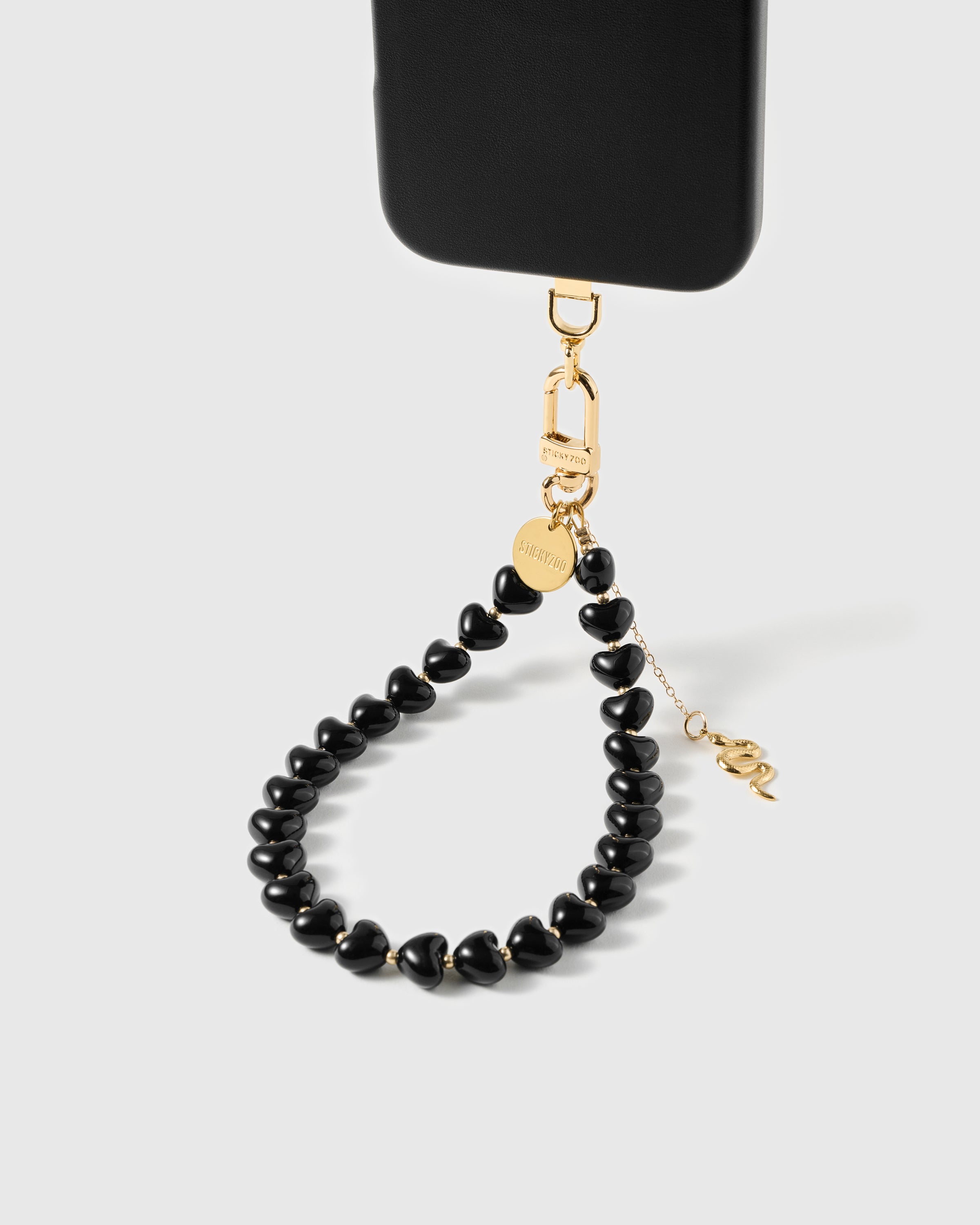 Loved by Thousands gold snake charm phone strap paired with phone case showing the drop chain hanging below the line of noir heart beads