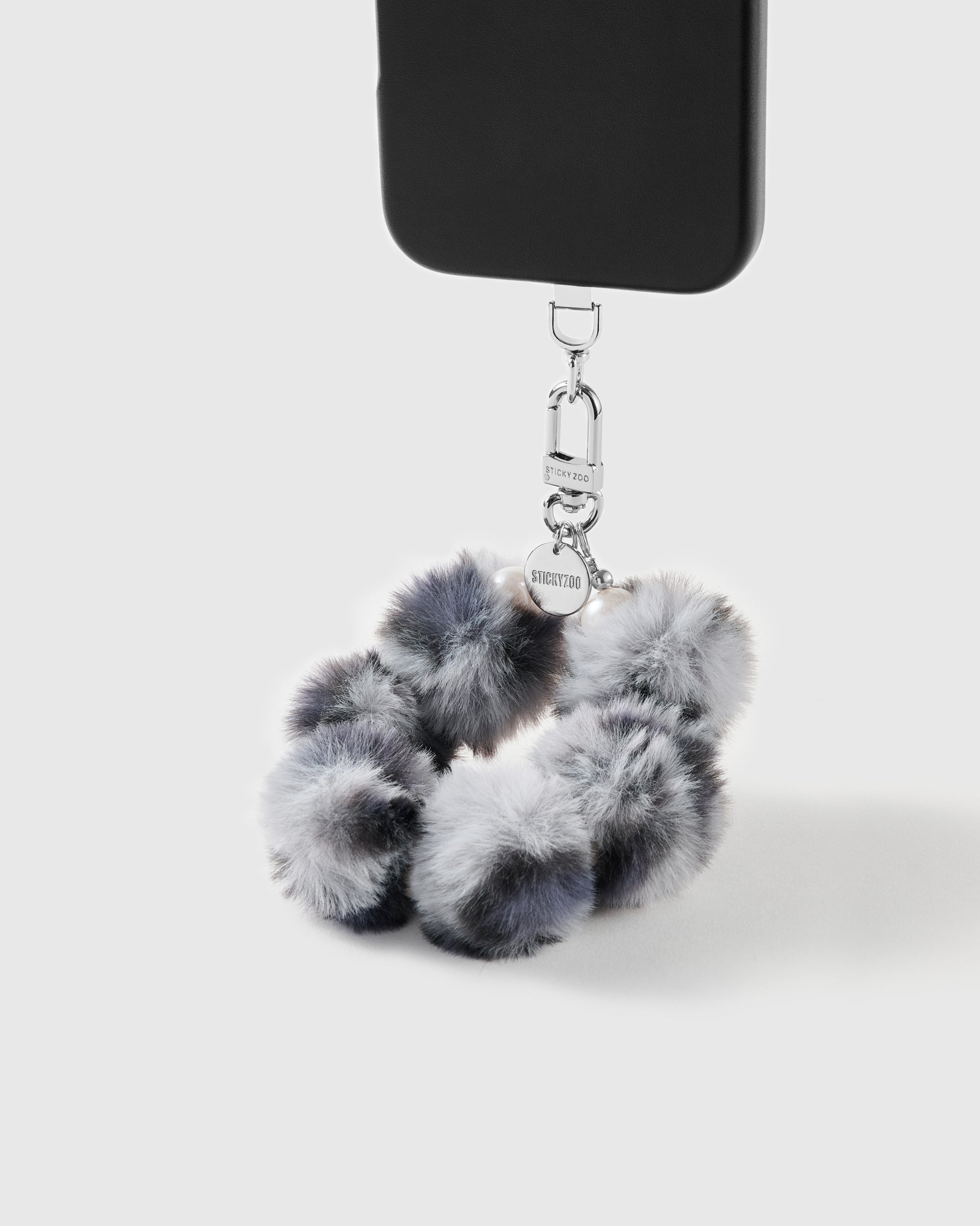 Smoke Pom wrist strap clipped to a black phone case for hands-free carry
