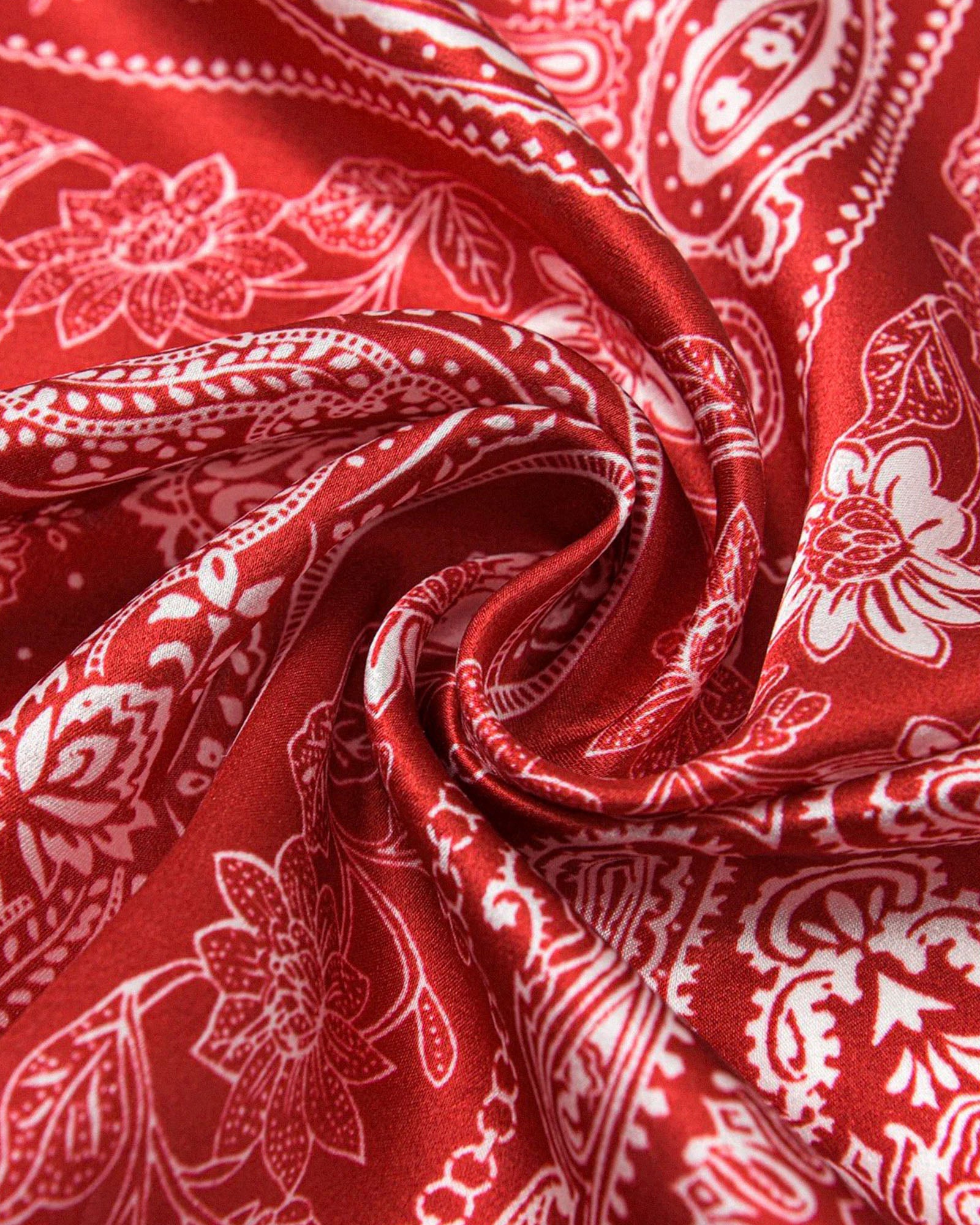 Close-up of the rouge silk twisted to show the soft drape and ivory paisley line-work
```