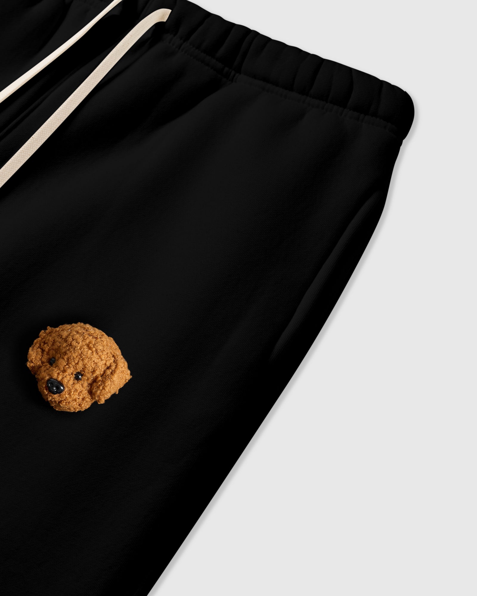 Close-up of plush poodle applique near pocket on black 350gsm cotton showing 3D texture
