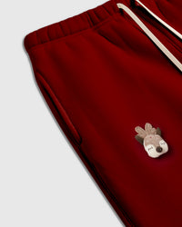 Detail of tartan-capped plush acorn applique with button center on red cotton
