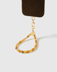 Beaded stone phone strap attached to a phone case with the gold clasp visible, showing universal fit with any case