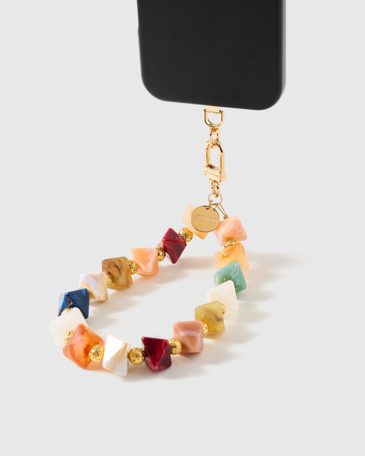 Marbled bead phone strap hanging from black phone case showing 18K gold-plated carabiner and STICKYZOO disc