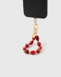 Ruby smoke agate phone strap hanging from black phone case showing deep red stone beads