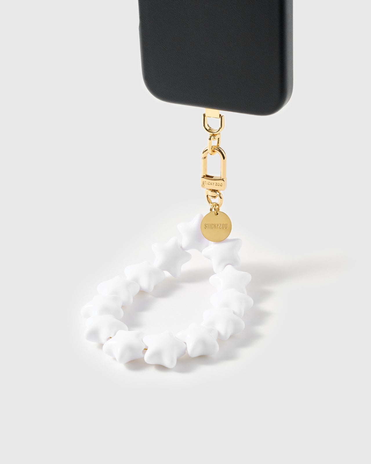 Ivory star bead strap hanging from a black phone case with gold-plated carabiner and engraved STICKYZOO disc — Loved by Thousands