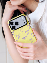 Butter bow phone case held near the face in everyday use with the lilac bow print on show