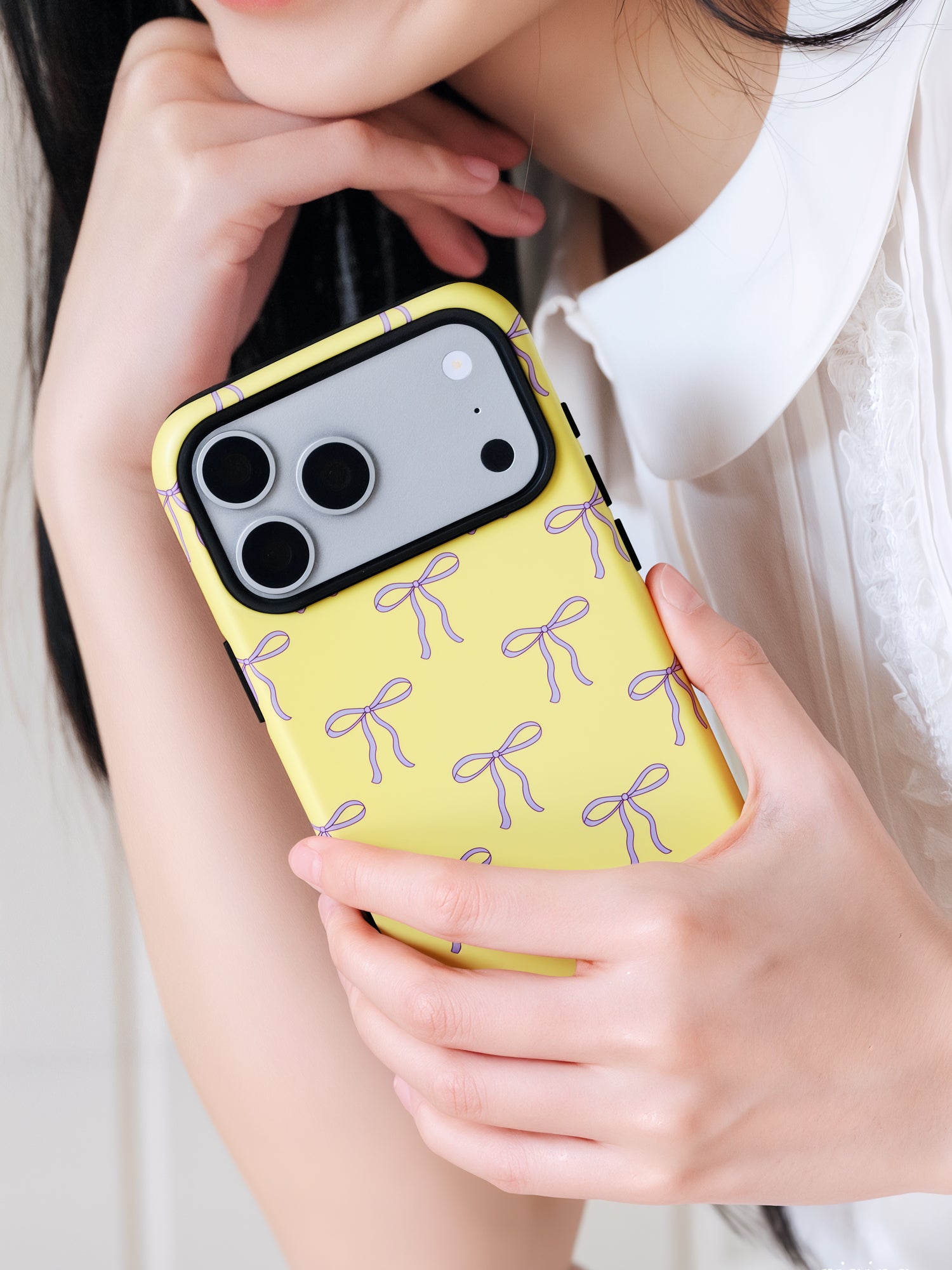 Butter bow phone case held near the face in everyday use with the lilac bow print on show