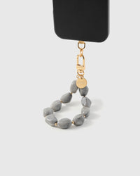 Grey marble stone phone strap hanging from black phone case showing wrist carry functionality