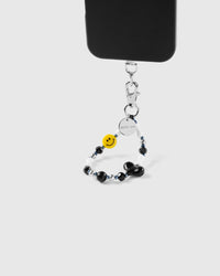 Black smiley heart phone strap attached to phone case showing wrist carry functionality