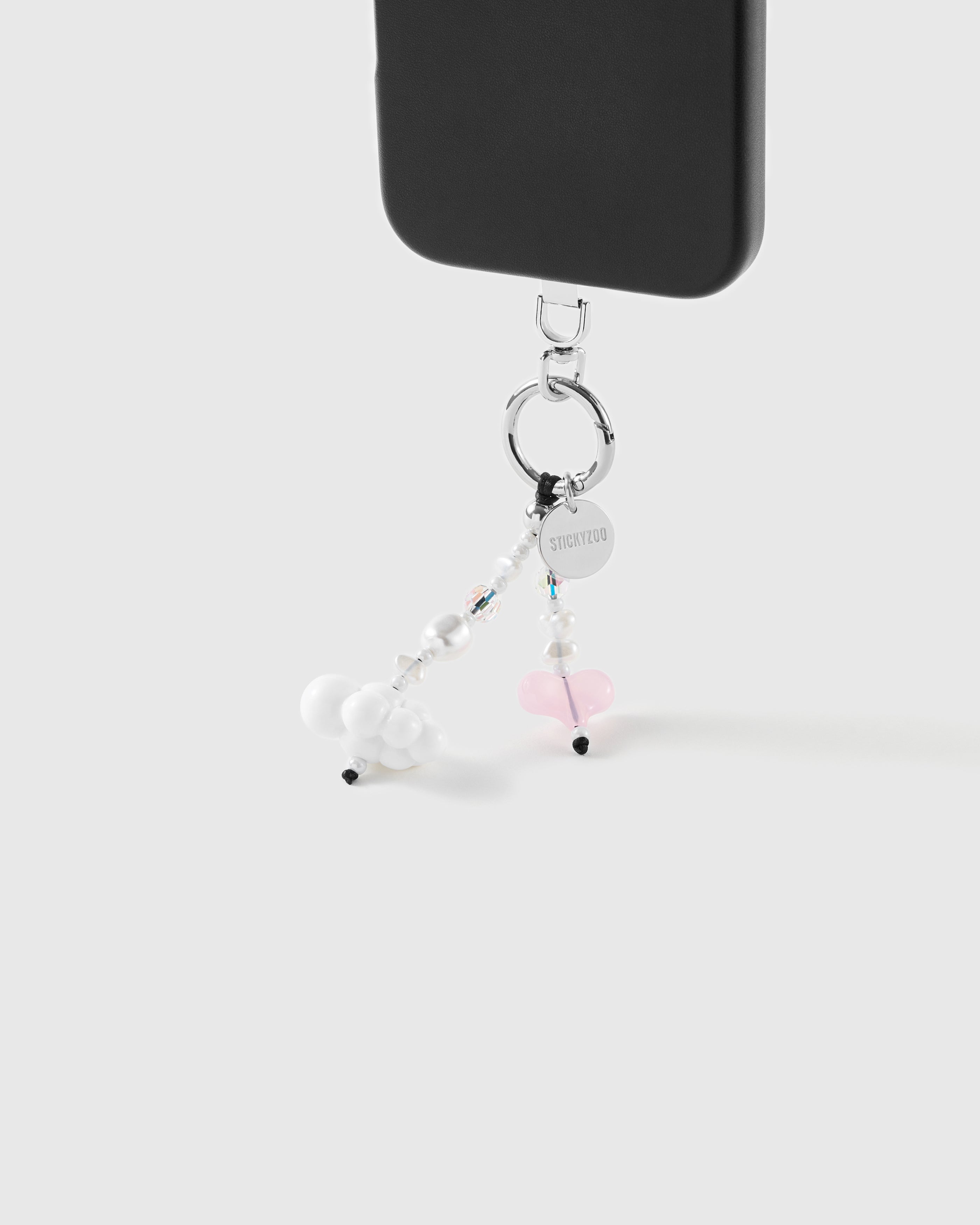 White cloud and pink jelly heart beaded strap hanging from a black phone by a silver-tone ring with engraved STICKYZOO disc.