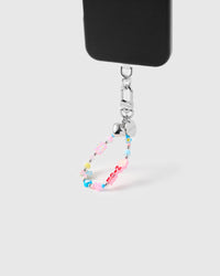 Blush flower cluster phone strap attached to black phone case showing wrist carry functionality