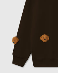 Detail of hand-stitched poodle faces on chocolate brown cotton showing tonal warmth and dimensional detail