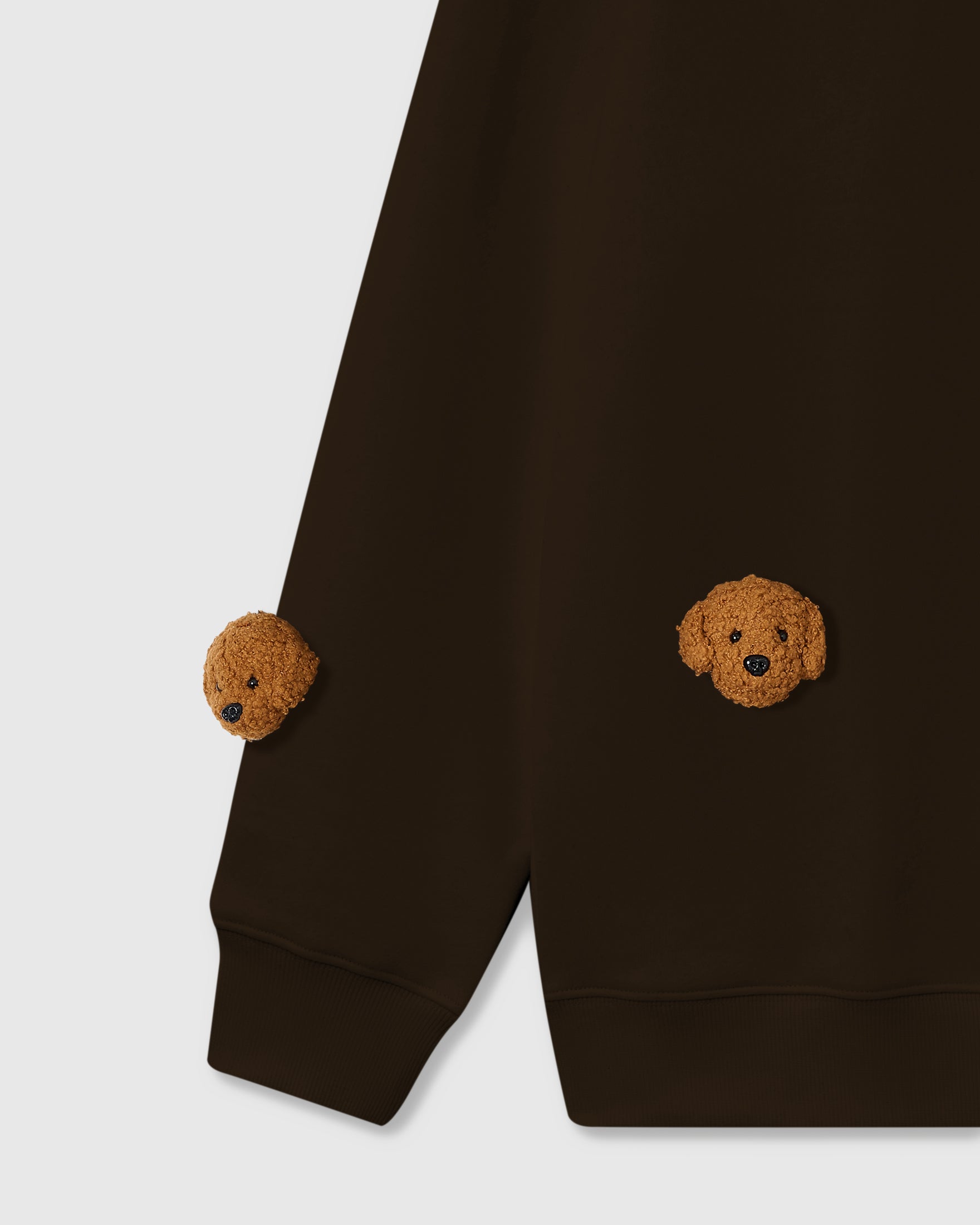 Detail of hand-stitched poodle faces on chocolate brown cotton showing tonal warmth and dimensional detail
