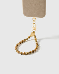 Tan stone bead phone strap attached to a phone case with the gold-plated clasp visible, showing universal fit with any case.