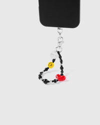 Noir heart smiley phone strap hanging from black phone case showing wrist carry