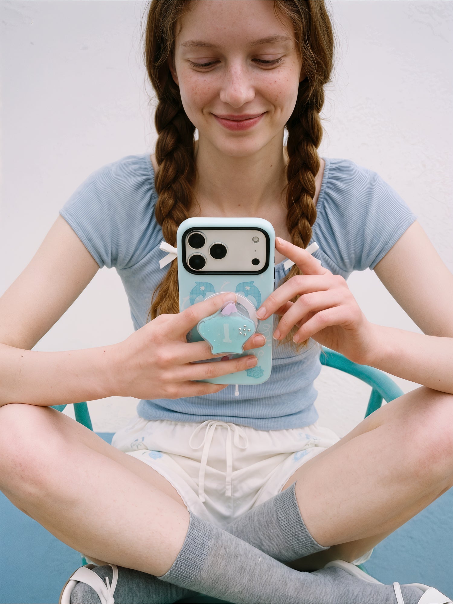 Phone held with fingers gripping the retractable MagSafe pop-grip on the back of the dolphin cove case