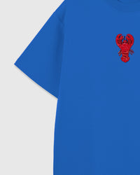 Detail of the raised lobster applique near the shoulder showing sequin tail scales and beaded antennae sewn onto blue cotton.