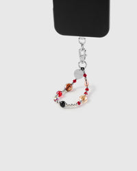 Red faceted glass bead phone strap hanging from black phone case showing daily carry