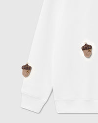 Detail of tartan-capped plush acorn with button center on white cotton sweatshirt