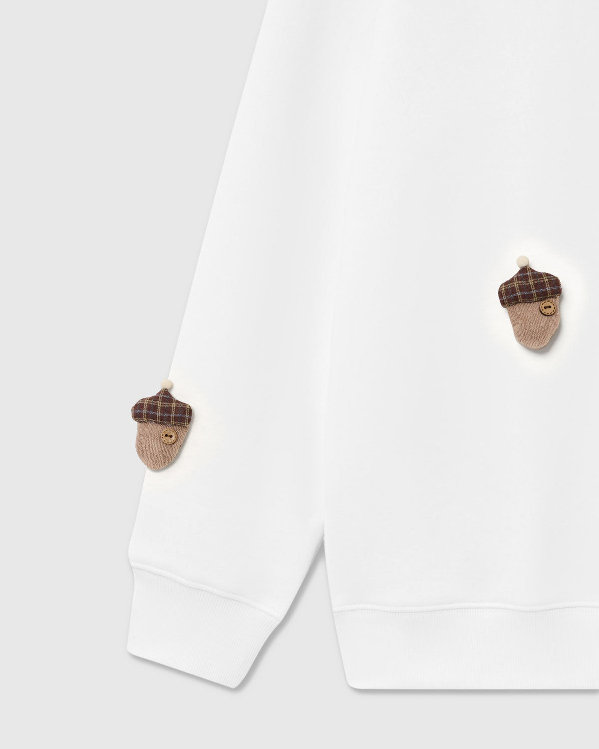{{Kept by 99% of buyers}} Detail of tartan-capped plush acorn with button center on white cotton sweatshirt