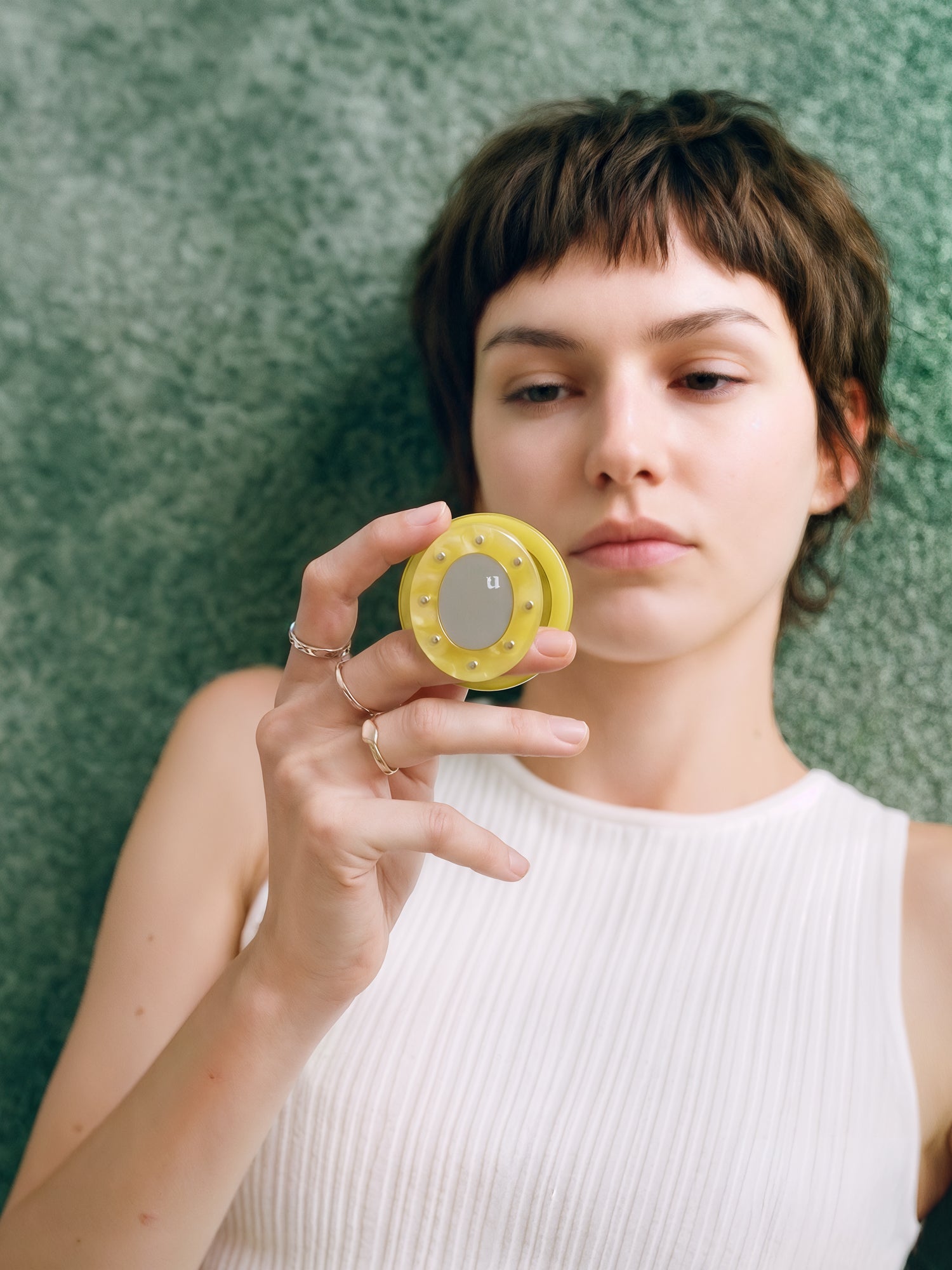 Close hold of the yellow acrylic-resin grip medallion with its small mirror center on the green leopard case.