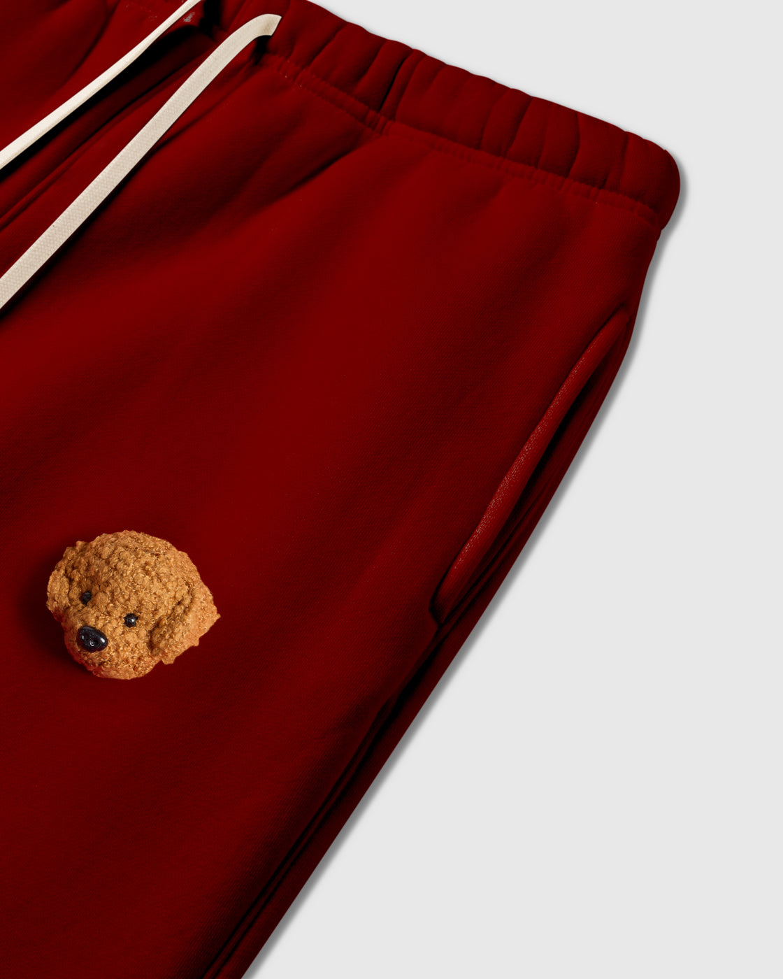 Close-up of plush poodle applique near pocket on red 350gsm cotton showing 3D texture