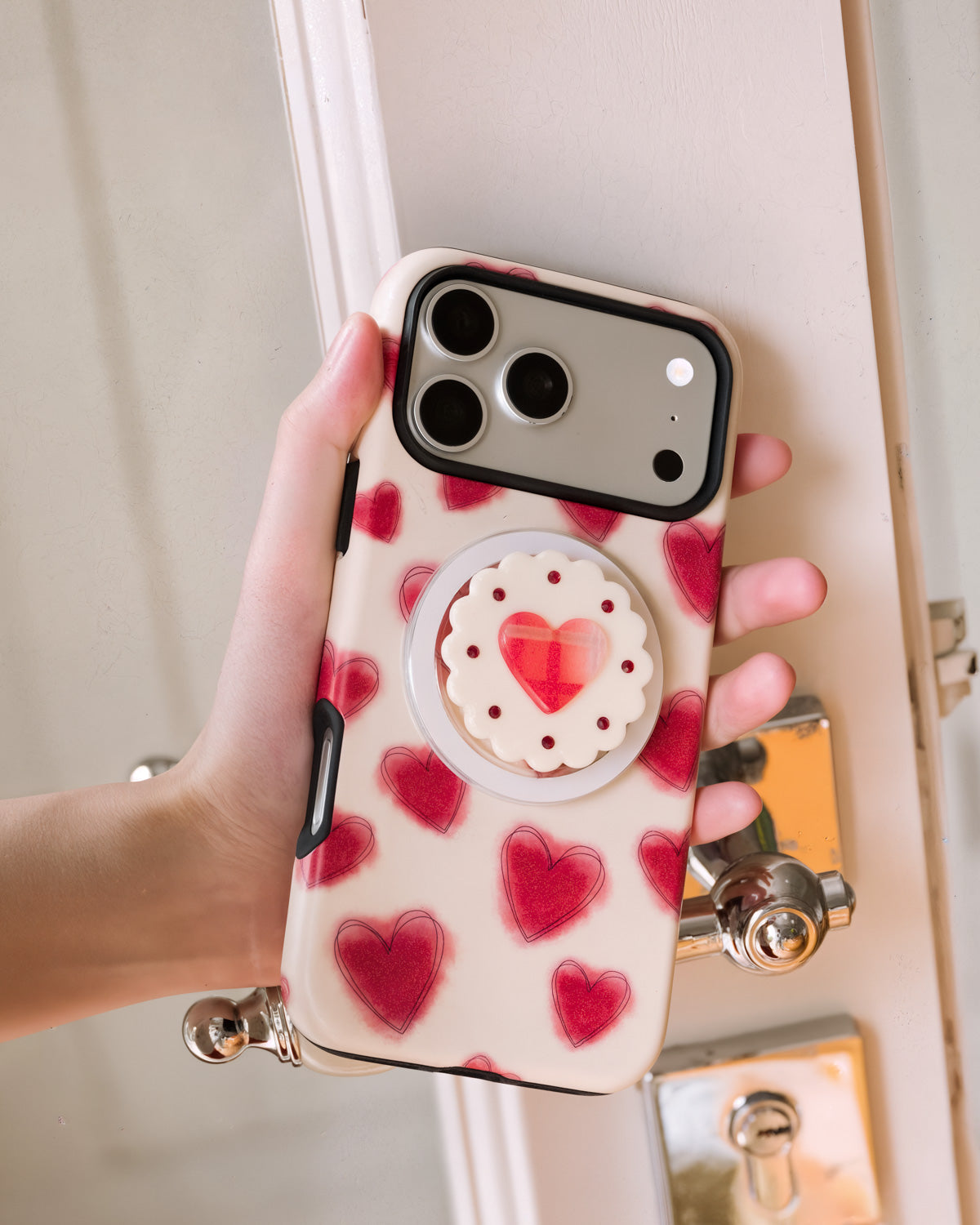 Jam heart phone case held in hand showing the scalloped biscuit-shaped MagSafe grip on the back