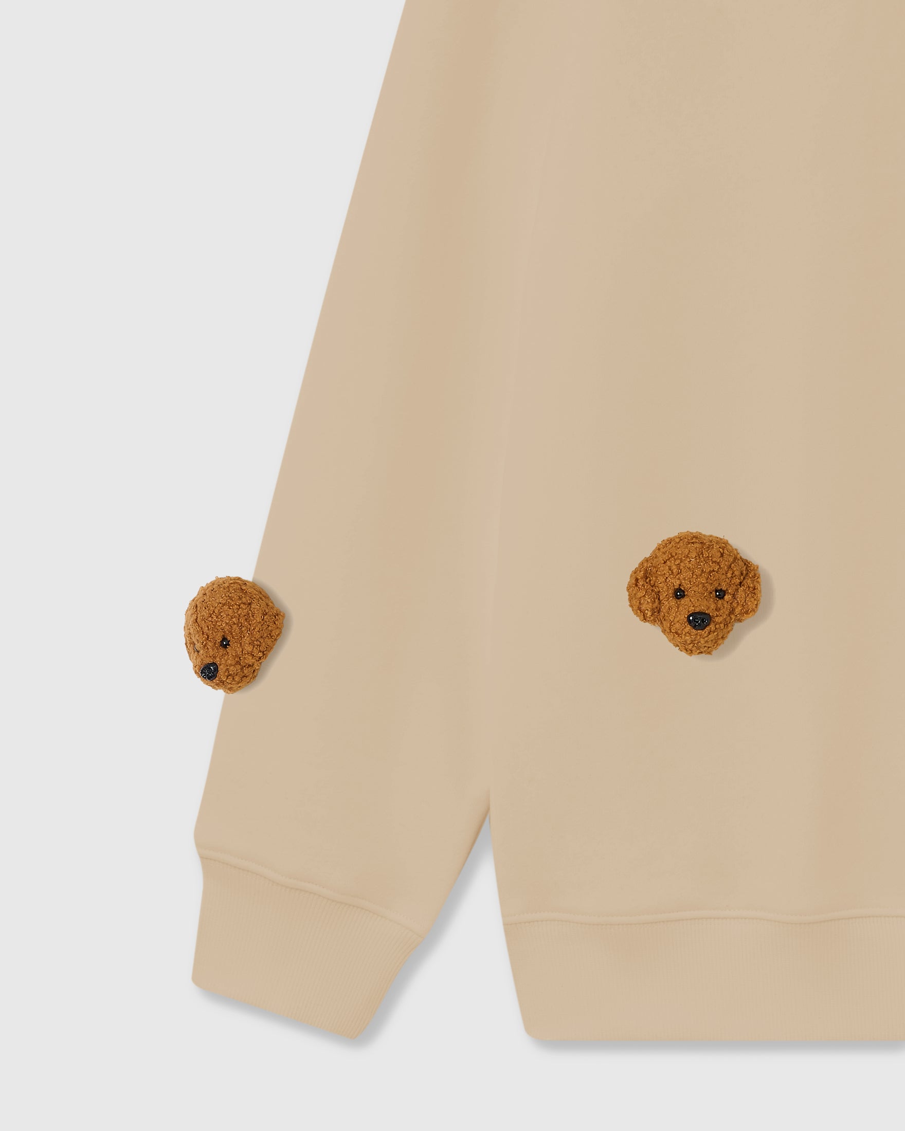 Detail of plush poodle appliques on beige cotton showing textured curly fur and embroidered eyes
