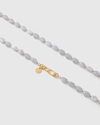 Close-up of grey and white elongated marble-style beads with gold spacers and engraved hardware
