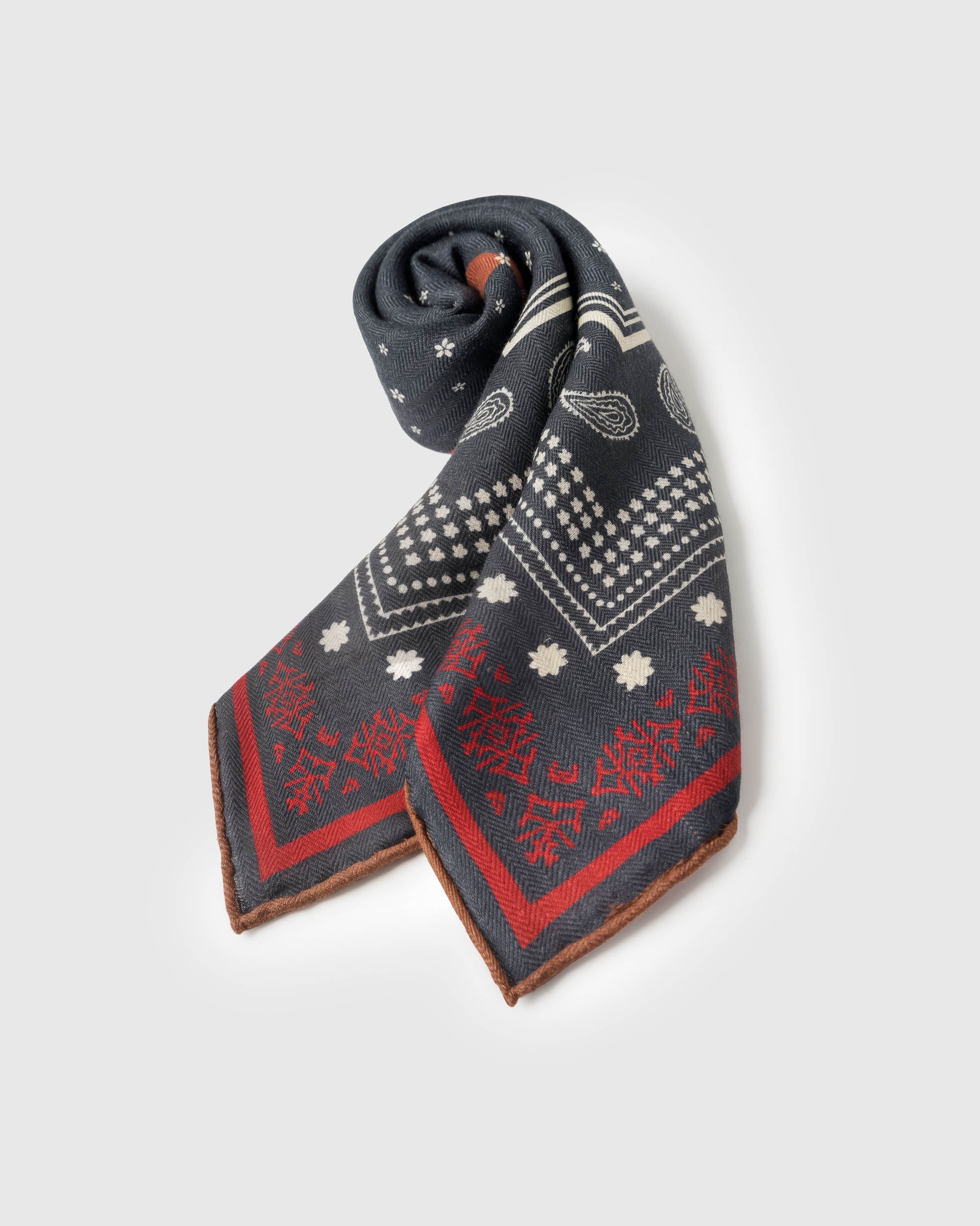 STICKYZOO saddle bandana silk scarf rolled into a soft twist showing the navy paisley and rust quadrants