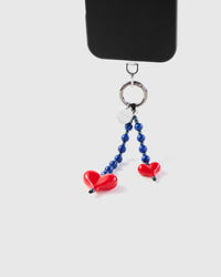 Blue stone and red heart dangle strap hanging from black phone case