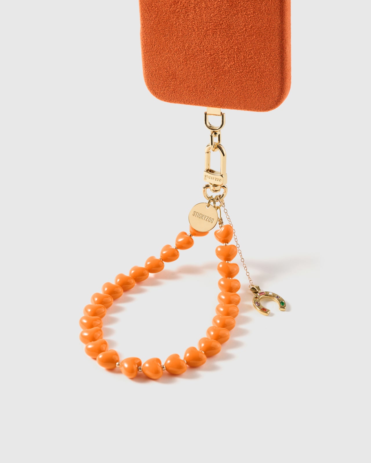 {Points up to catch luck} Close-up of gold horseshoe charm set with tiny rainbow-coloured stones on fine drop chain
