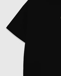 Dropped-shoulder construction of the black oversized cotton tee with the beaded lemon appliqué visible at the chest, cut in 230gsm cool-touch cotton