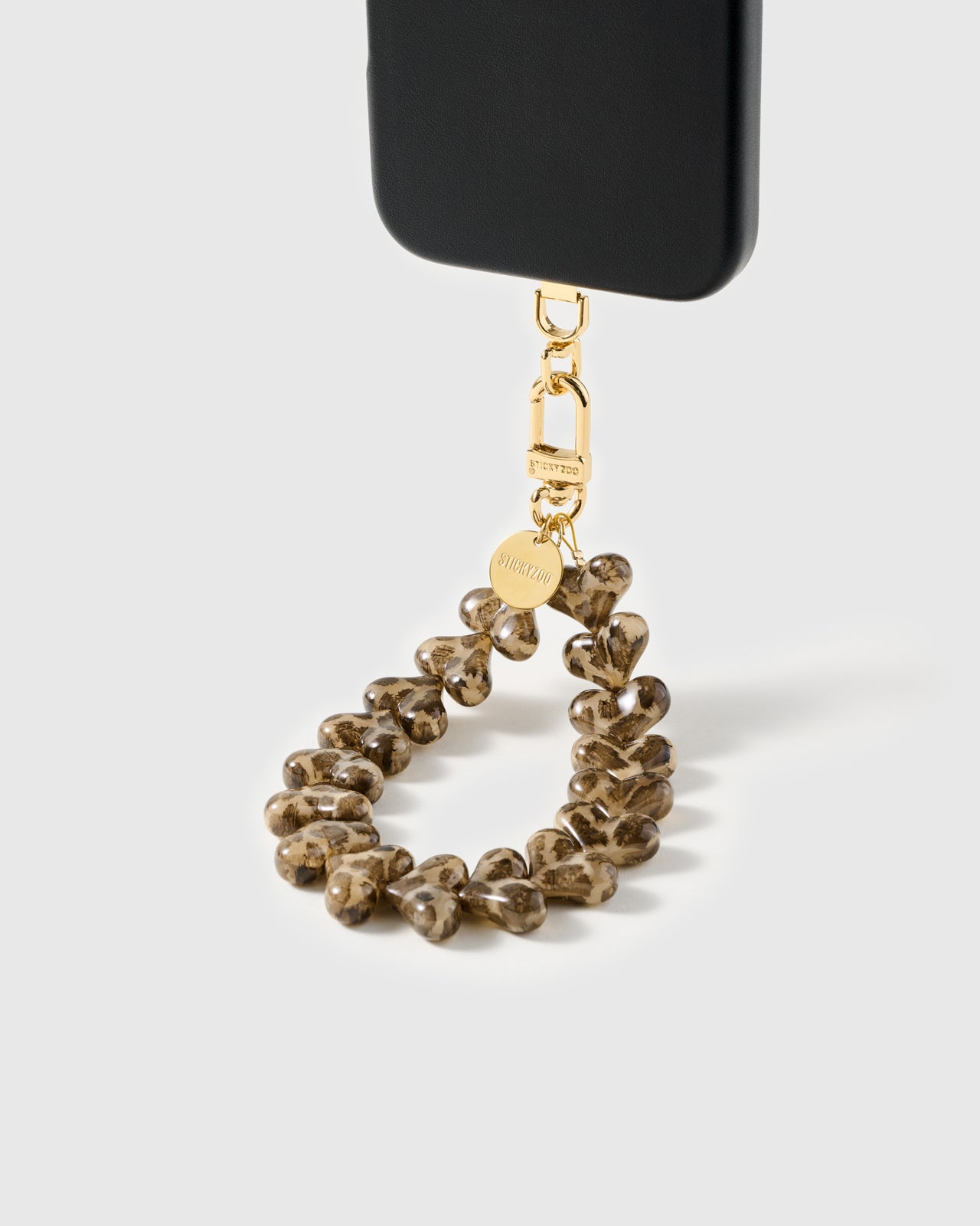 Loved by Thousands leopard print phone strap paired with phone case showing the line of patterned heart beads hanging from the gold carabiner