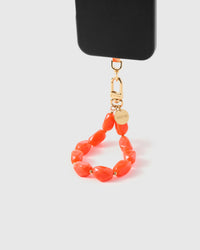 Coral agate phone strap hanging from black phone case showing wrist carry functionality