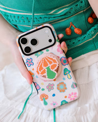Phone held in hand with fingers wrapped around the retractable MagSafe grip on the pixel mushroom case