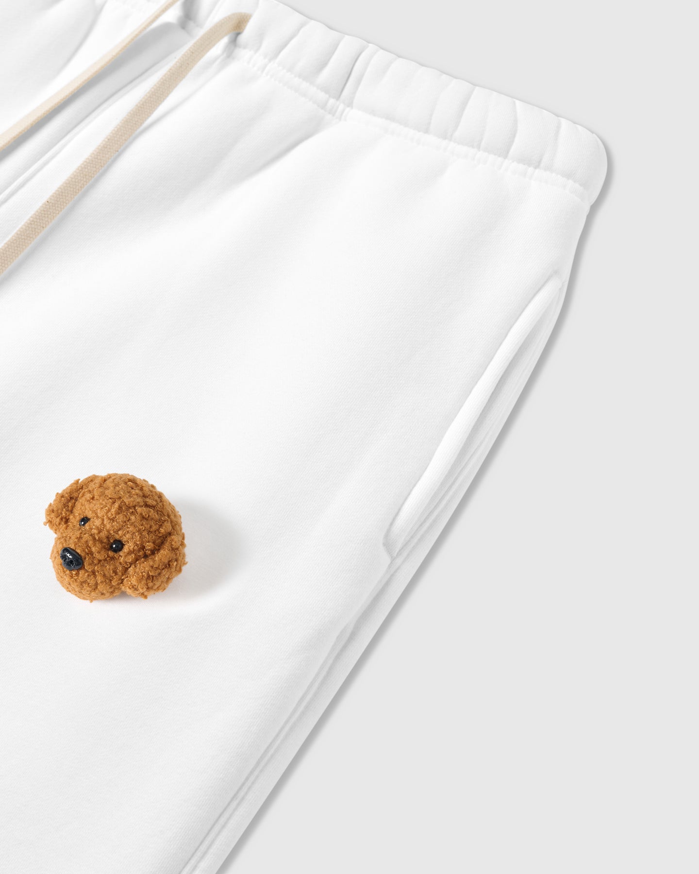 Close-up of plush poodle applique near pocket on white 350gsm cotton showing 3D texture