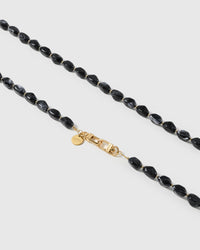 Macro close-up of polished black resin nugget beads and gold-plated clasp on the handmade NOIR ORBIT cross-body strap
