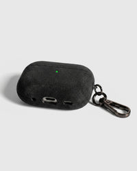 Back view of dark charcoal Alcantara case showing USB-C port, speaker cutouts, and metal carabiner