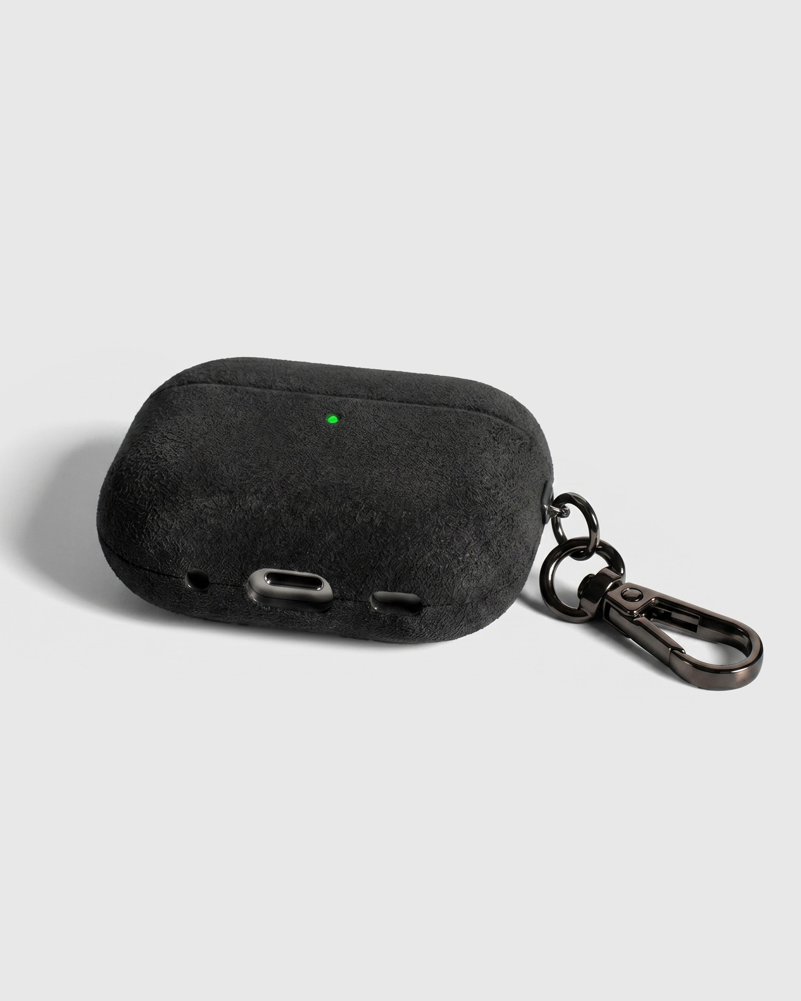 Back view of dark charcoal Alcantara case showing USB-C port, speaker cutouts, and metal carabiner