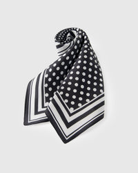 Black and white polka-dot silk scarf rolled and knotted to show the small-square format and graphic frame
```