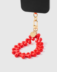 Red heart bead phone strap hanging from black phone case showing wrist carry functionality